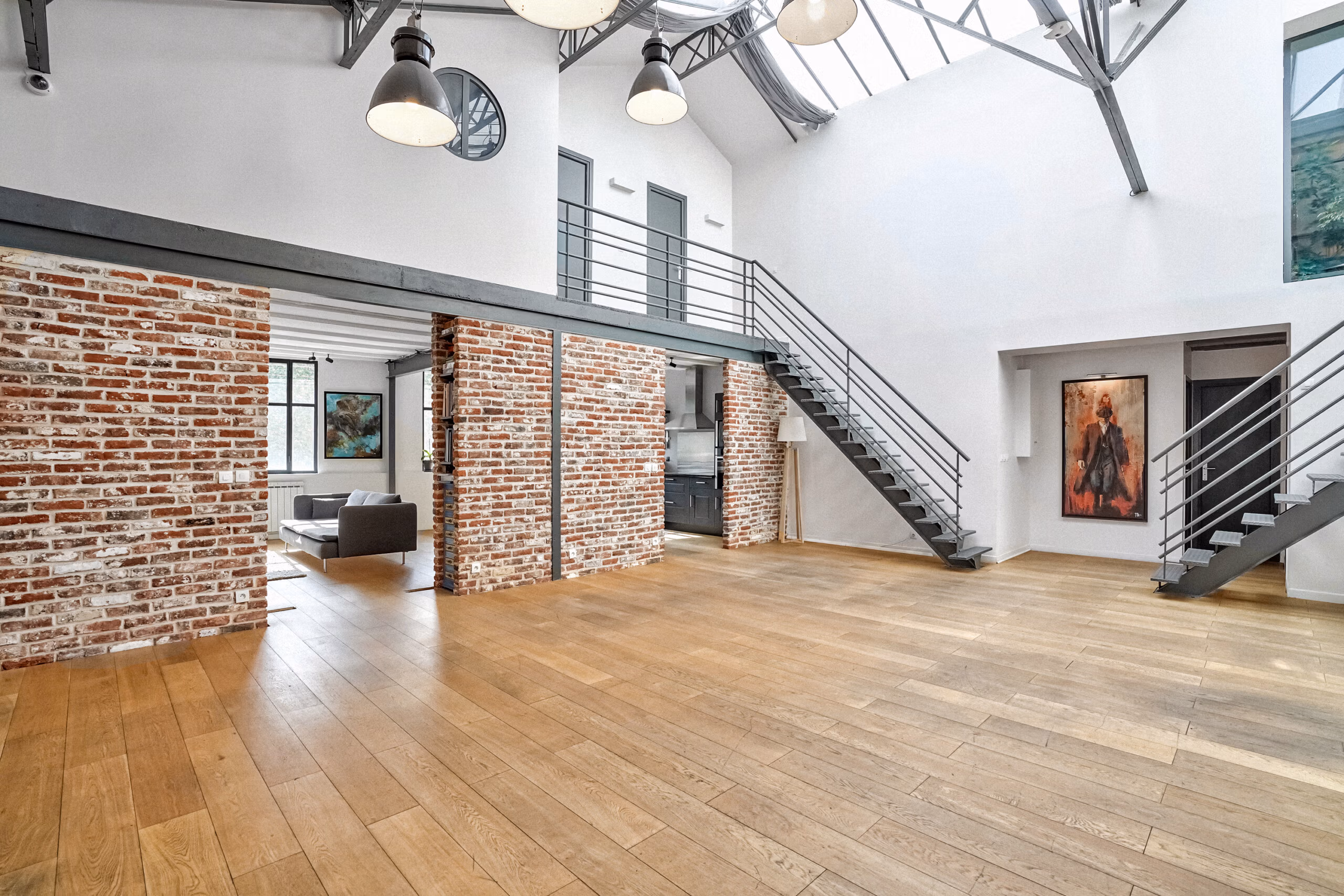 Grande pièce principale du loft avec ambiance Brooklyn New York, murs de briques apparentes d'époque, parquet bois massif et double hauteur pour tournages cinéma et shootings photo