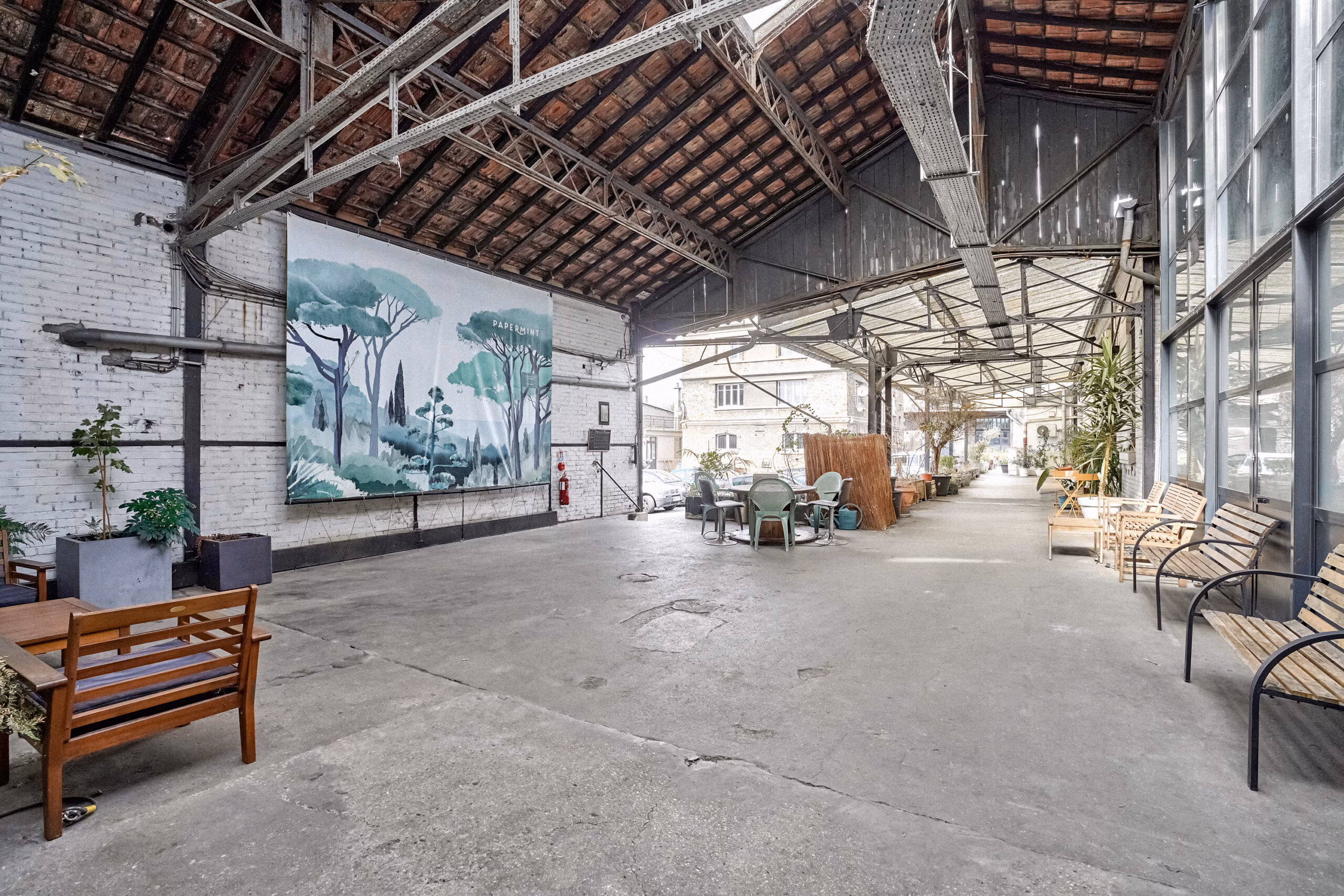 Quai extérieur des anciens entrepôts SNCF réhabilités avec charpente métallique apparente, murs briques et sol béton brut pour tournages décor industriel authentique