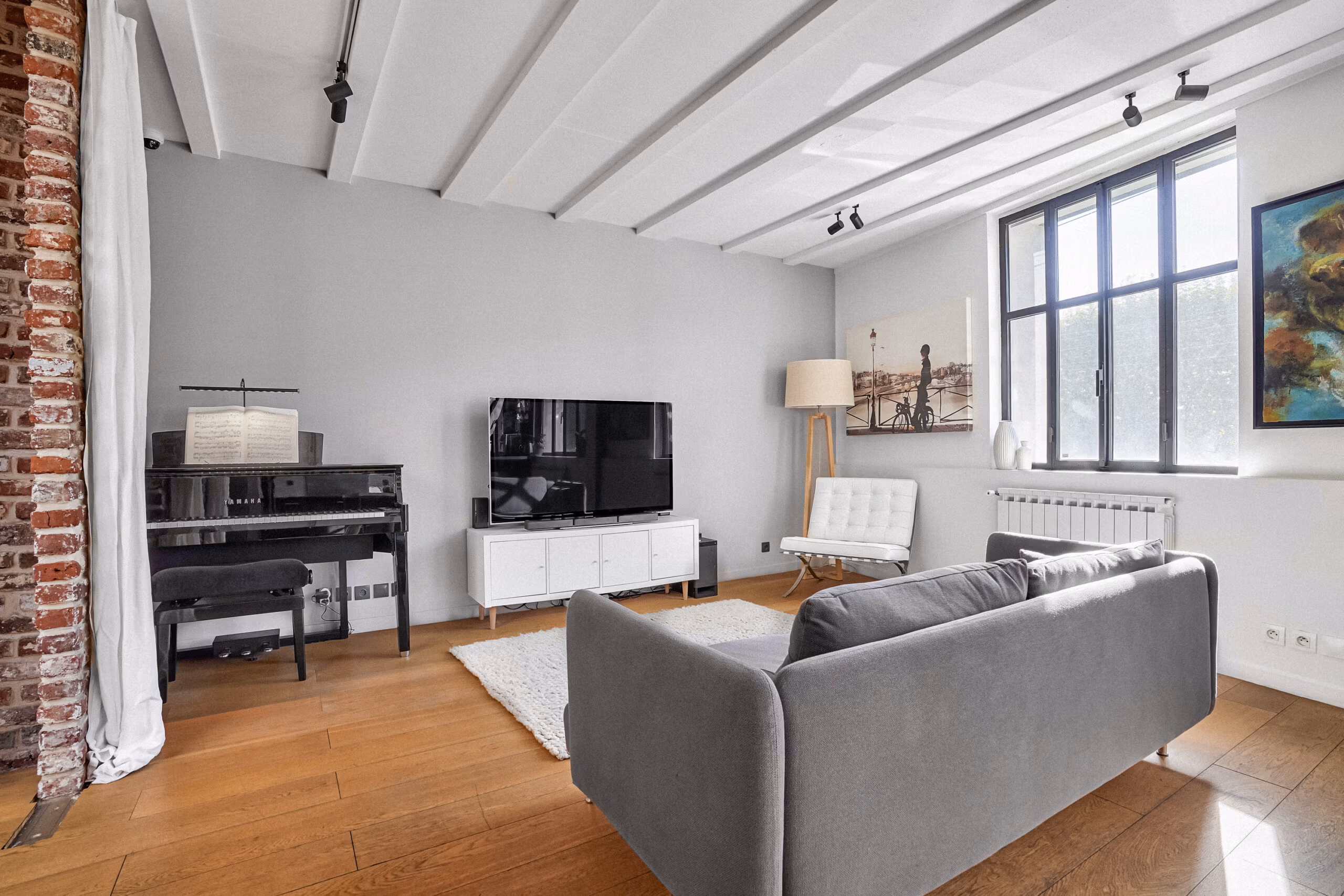 Salon avec piano noir, mobilier design iconique et œuvres murales créant une ambiance rétro-chic pour productions audiovisuelles et shootings déco