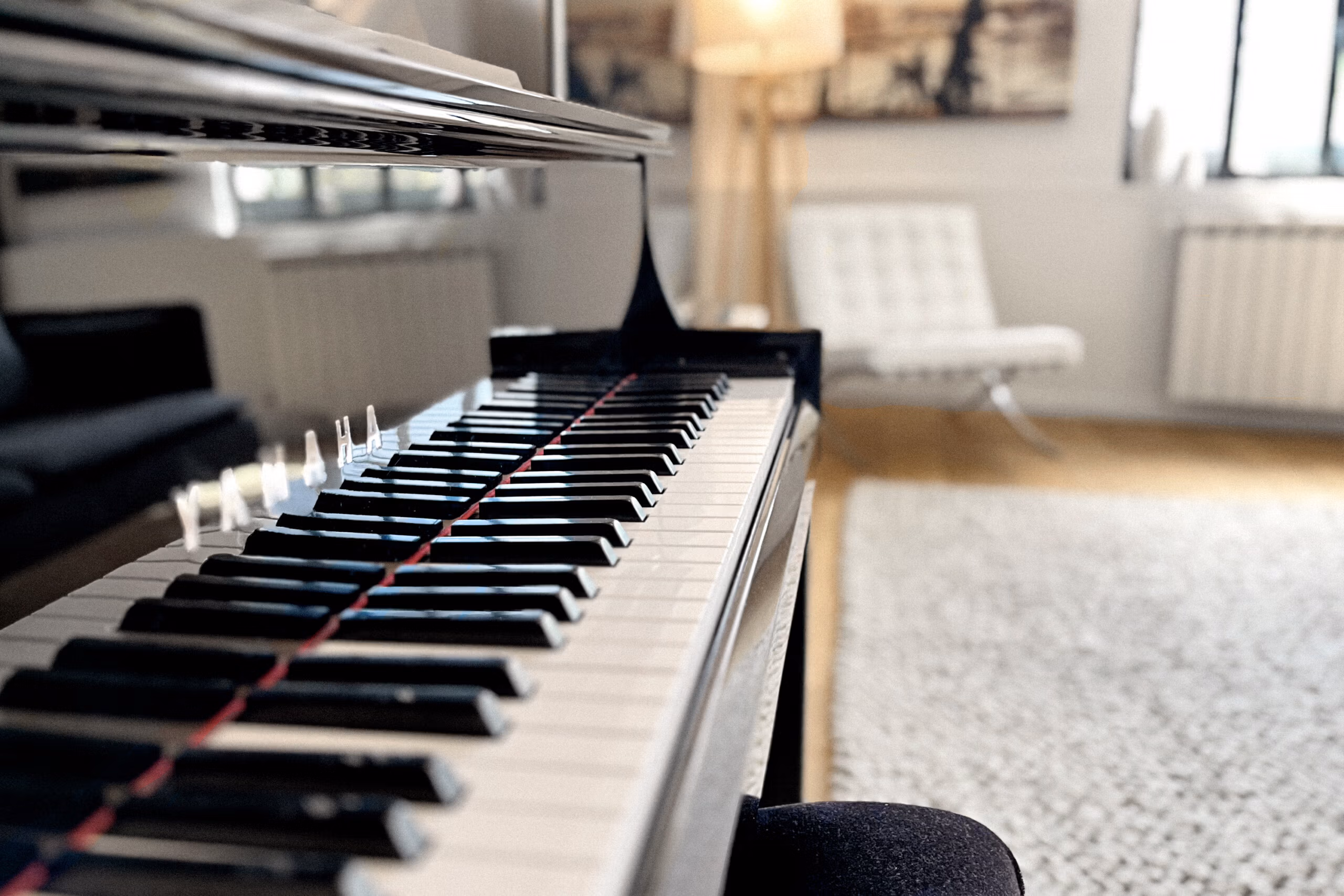 Détail piano noir dans le salon avec parquet bois et lumière naturelle, créant un décor musical authentique pour clips et productions artistiques