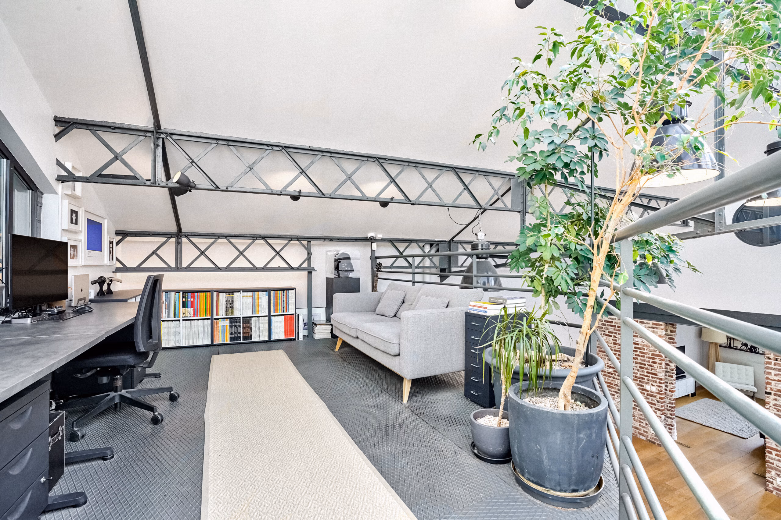 Mezzanine bureau avec végétation intérieure XXL, poutres métalliques triangulées, bibliothèque et espace lounge