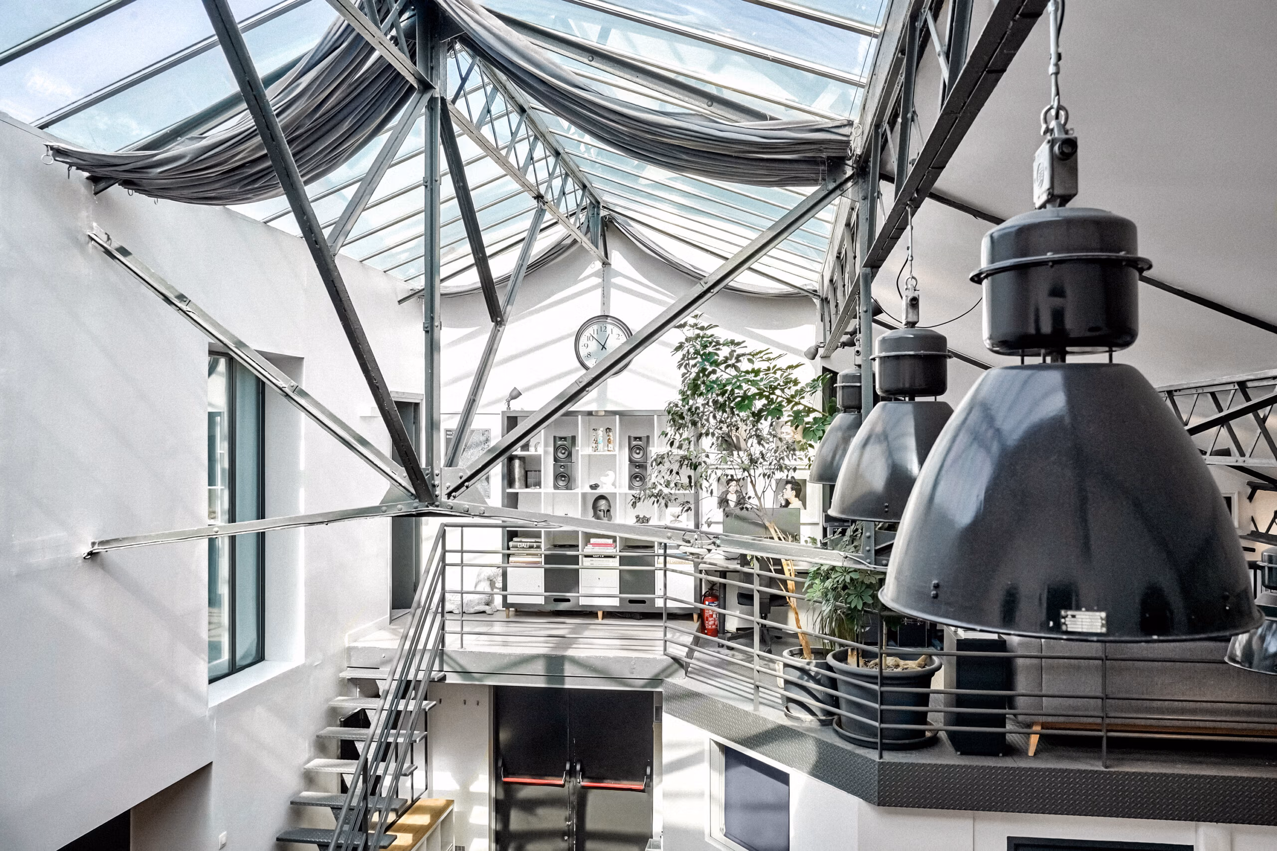 Architecture intérieure avec verrière cathédrale centrale, passerelles métalliques, Suspensions XXL et végétation haute