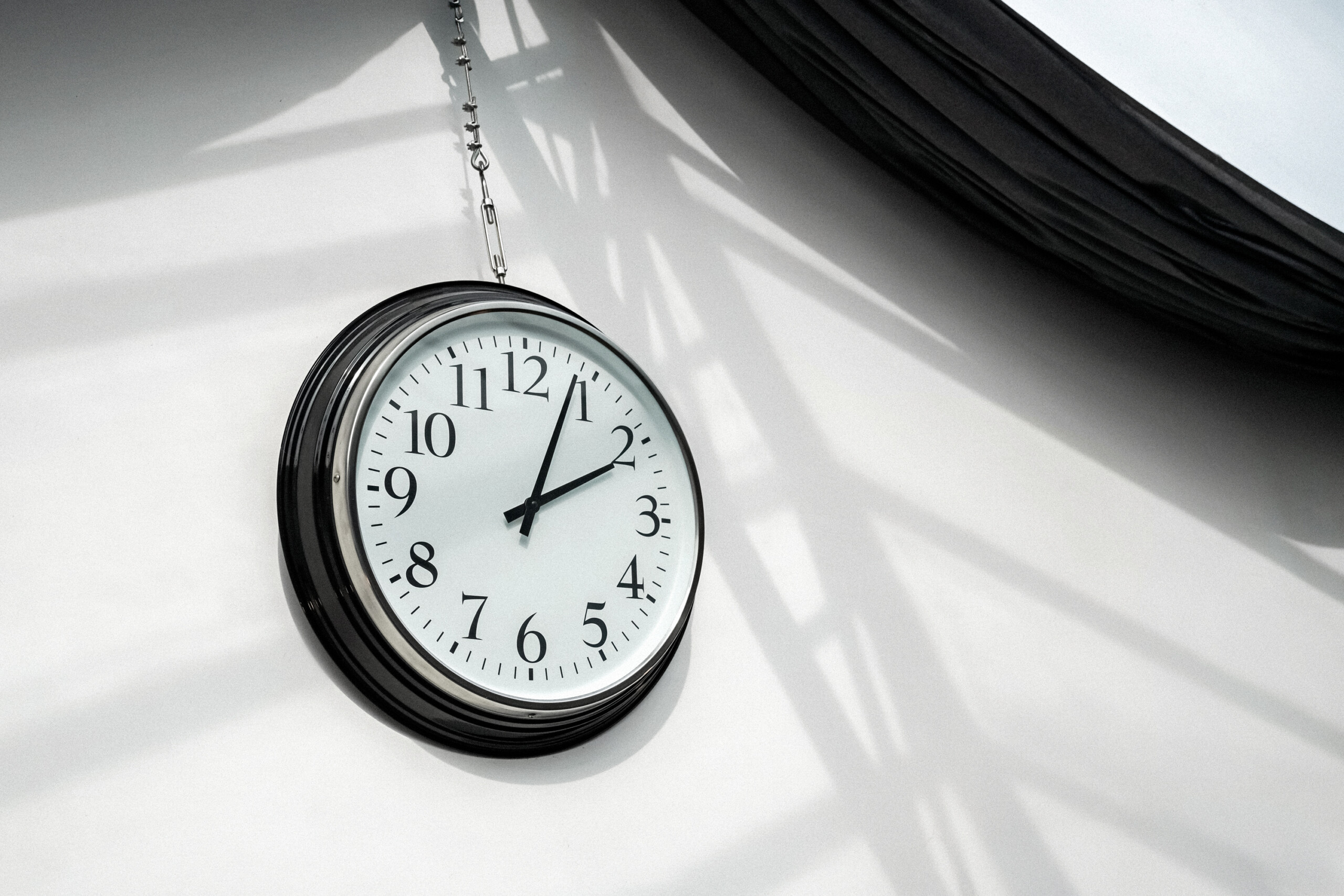 Horloge industrielle suspendue avec jeux d'ombres graphiques créés par la verrière, détail décoratif authentique pour tournages d'ambiance et shootings