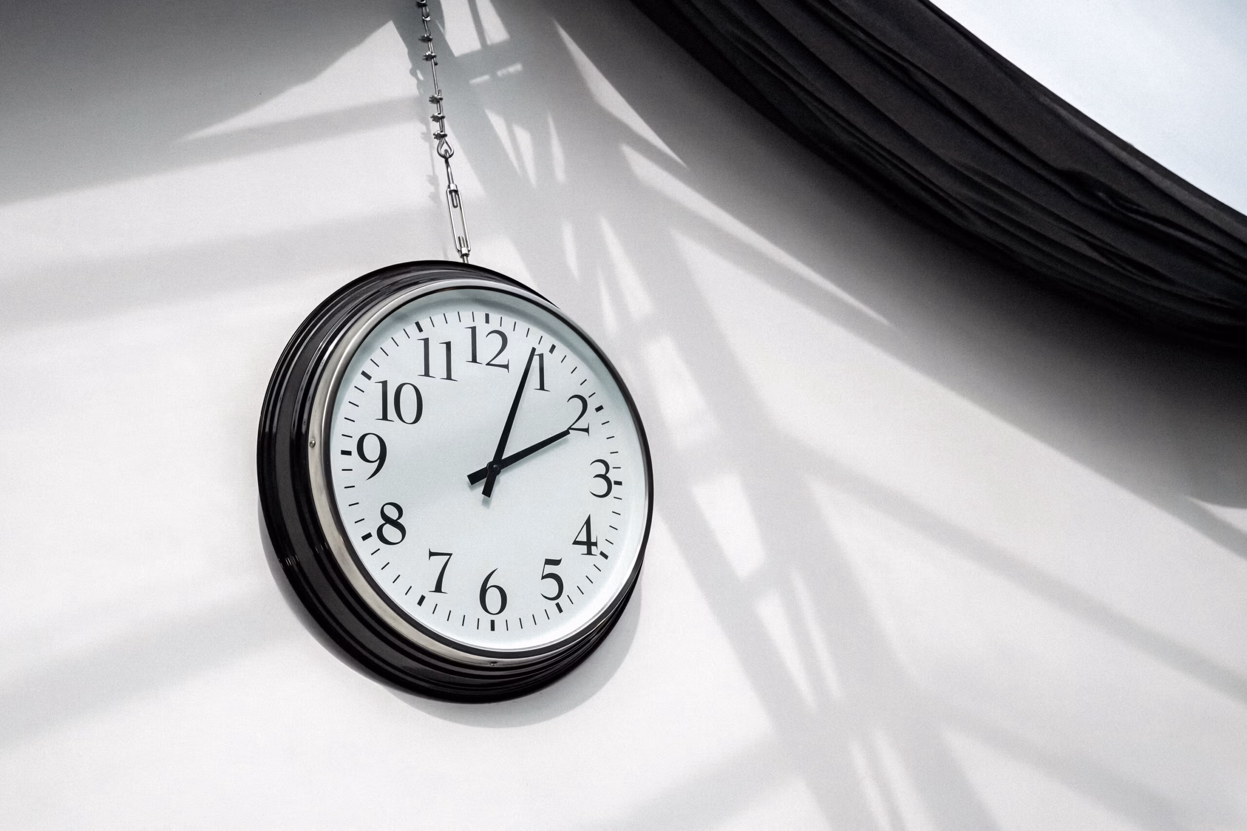 Horloge industrielle suspendue avec jeux d'ombres graphiques créés par la verrière, détail décoratif authentique pour tournages d'ambiance et shootings