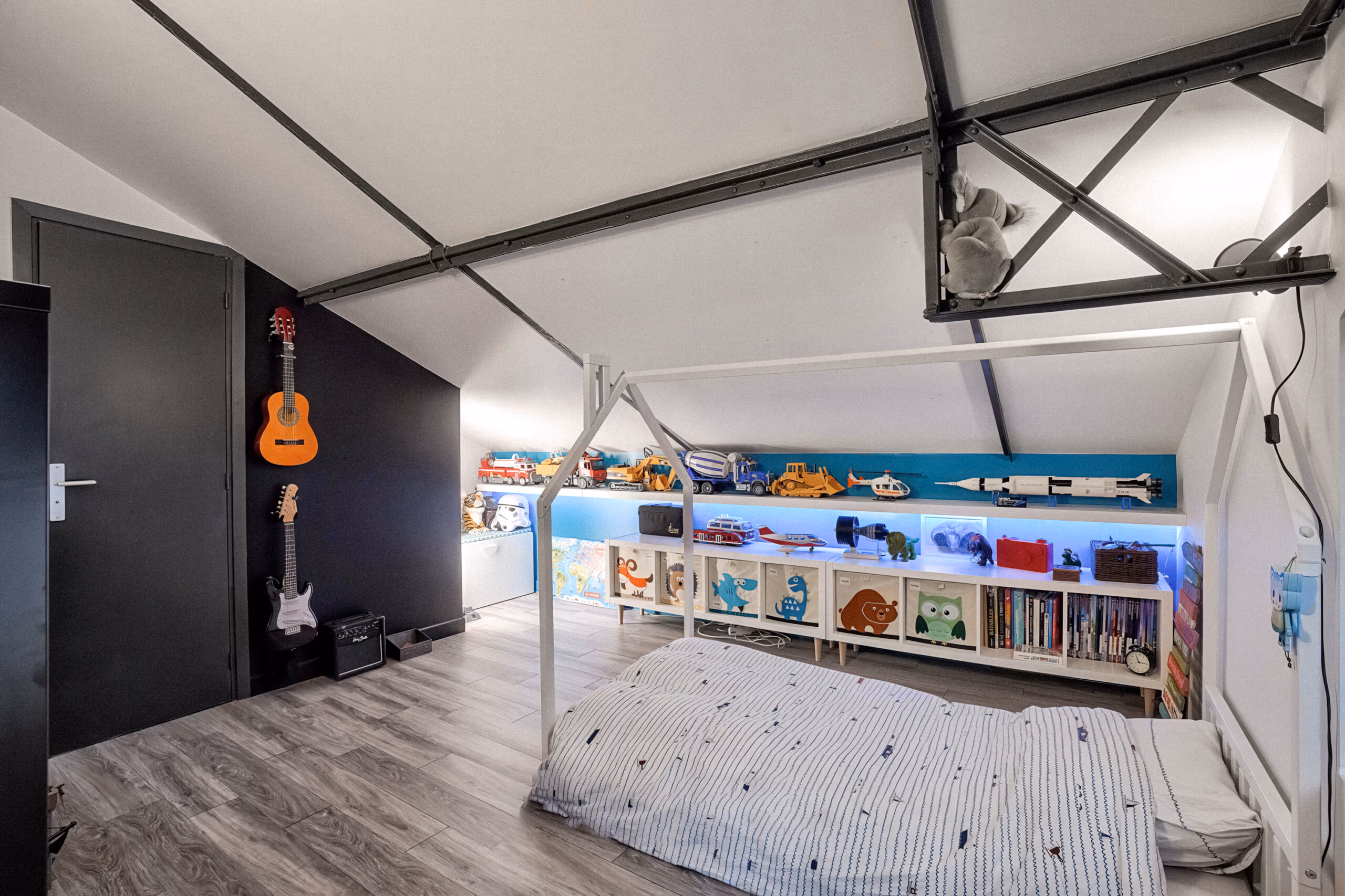 Chambre enfant (garçon) avec guitares suspendues, étagères rangement colorées rétro-éclairées et parquet bois pour shootings famille et contenus parentalité lifestyle