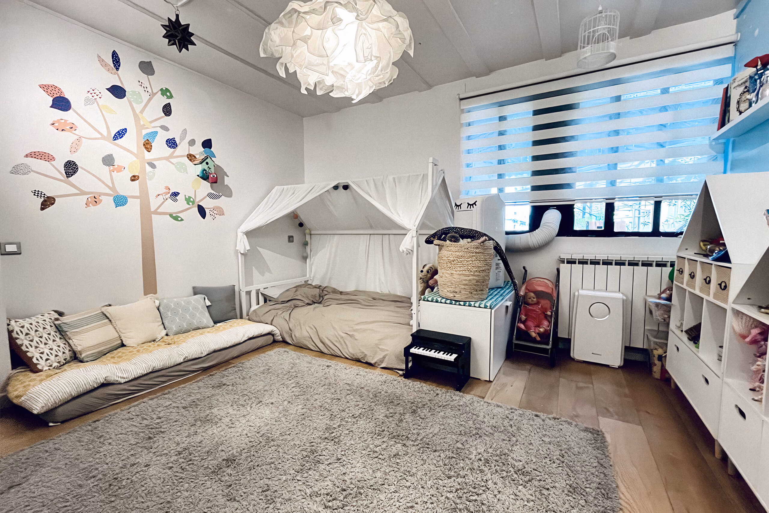 Chambre enfant (fille) avec lit cabane design, décoration murale arbre coloré et luminaire suspension origami pour tournages enfance et shootings déco jeune public