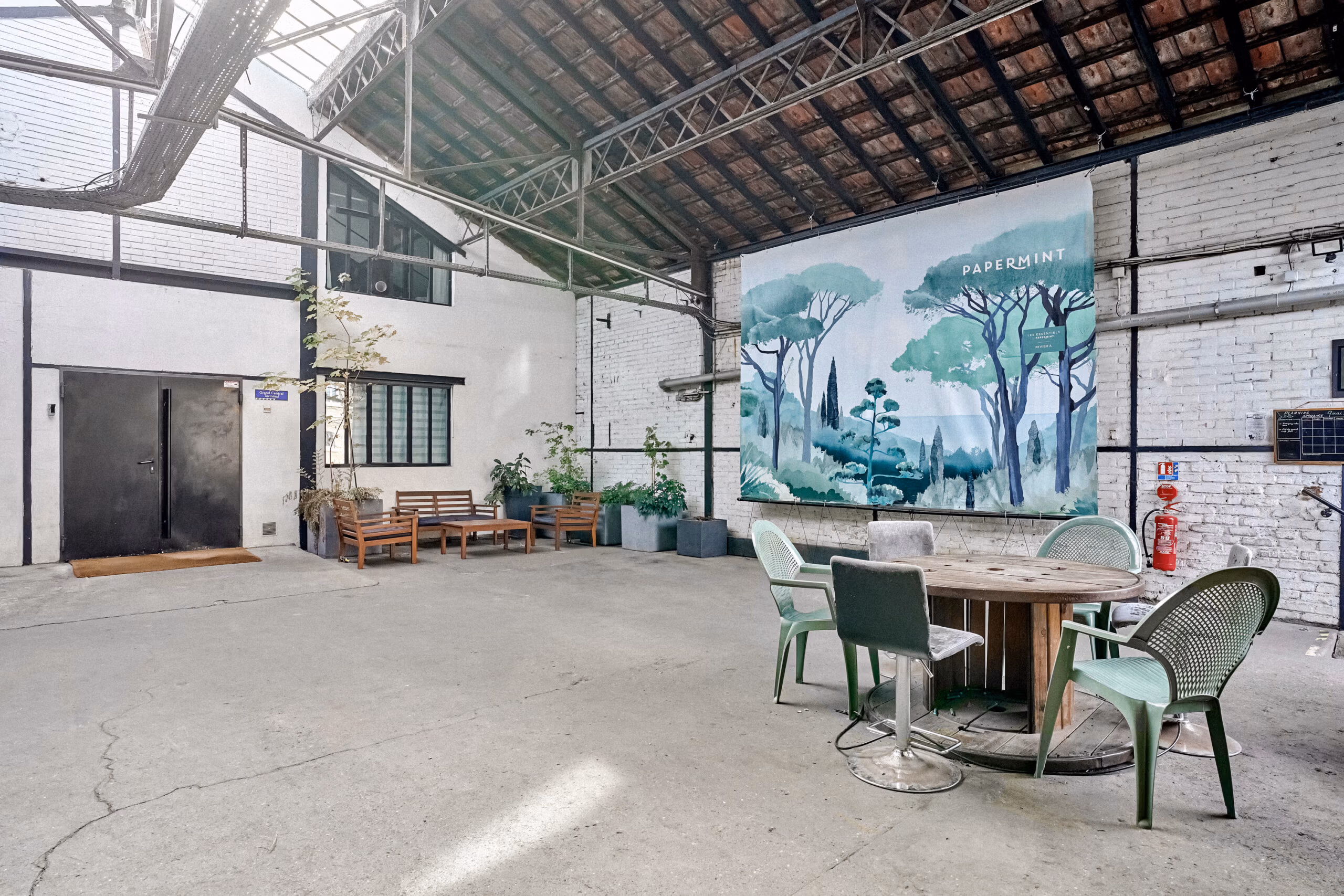 Quai couvert anciens entrepôts SNCF avec fresque murale aquarelle, charpente bois apparente et sol béton brut pour tournages décor industriel brut