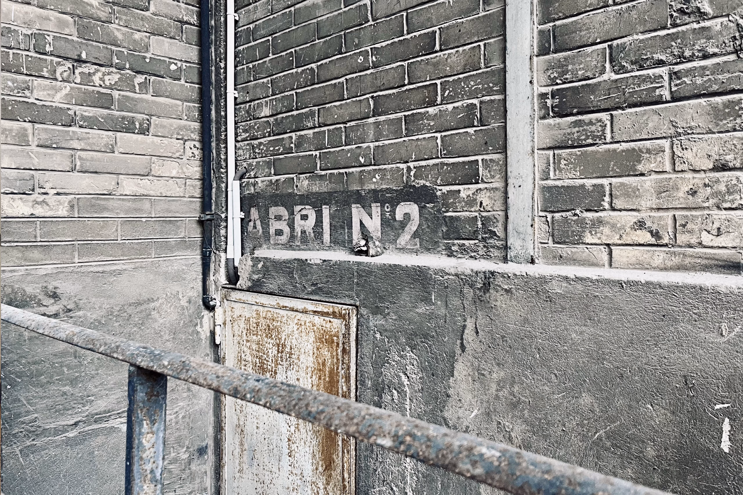 Détail authentique quai de chargement SNCF avec marquage Abri anti-aérien N°2 sur briques patinées et rail métallique, patrimoine ferroviaire pour contenus riches en histoire